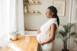 Pregnant woman smiling by sunny kitchen window